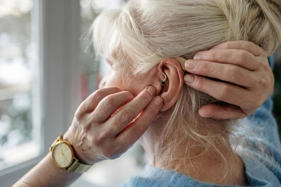A woman touching the hearing aid in her ear